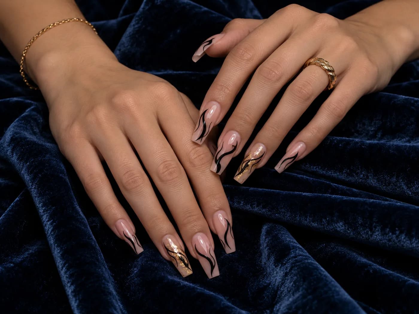 Nude nagels met zwarte en gouden swirls